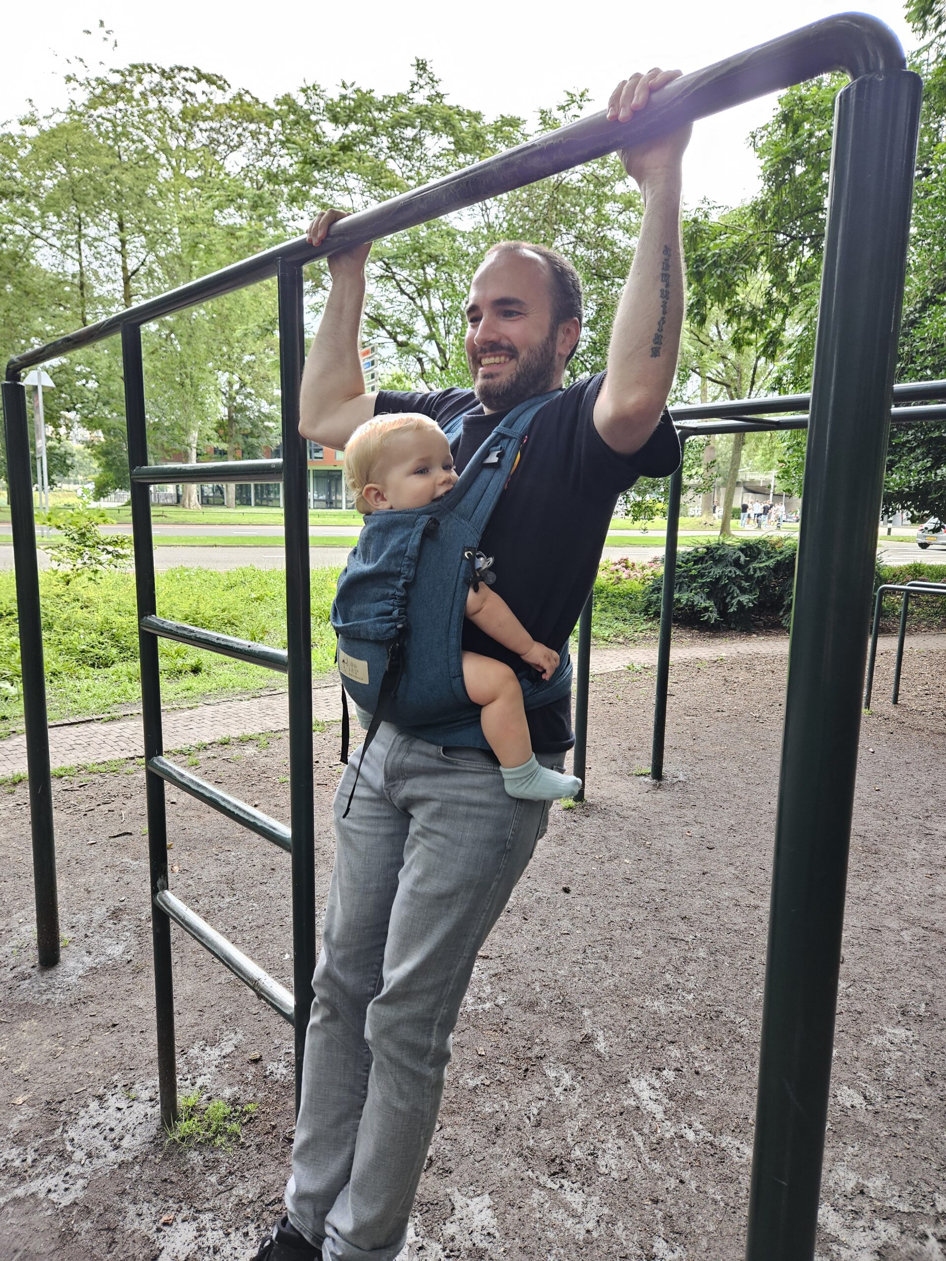 Home gym dad doing pull-up while holding baby — functional fitness and fatherhood